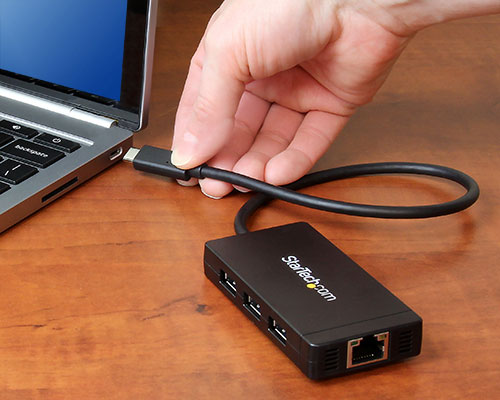 Photo showing the hub's USB and Gigabit Ethernet ports, as well as the hub being connected to a laptop's USB C port 