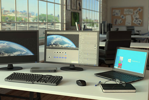 Foto della dock Thunderbolt 3 collegata a una workstation con due monitor 4K, in un ambiente professionale creativo