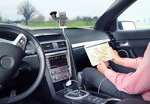 Ladda en iPhone i ett telefonställ i bilen och ladda samtidigt passagerarens Samsung-surfplatta